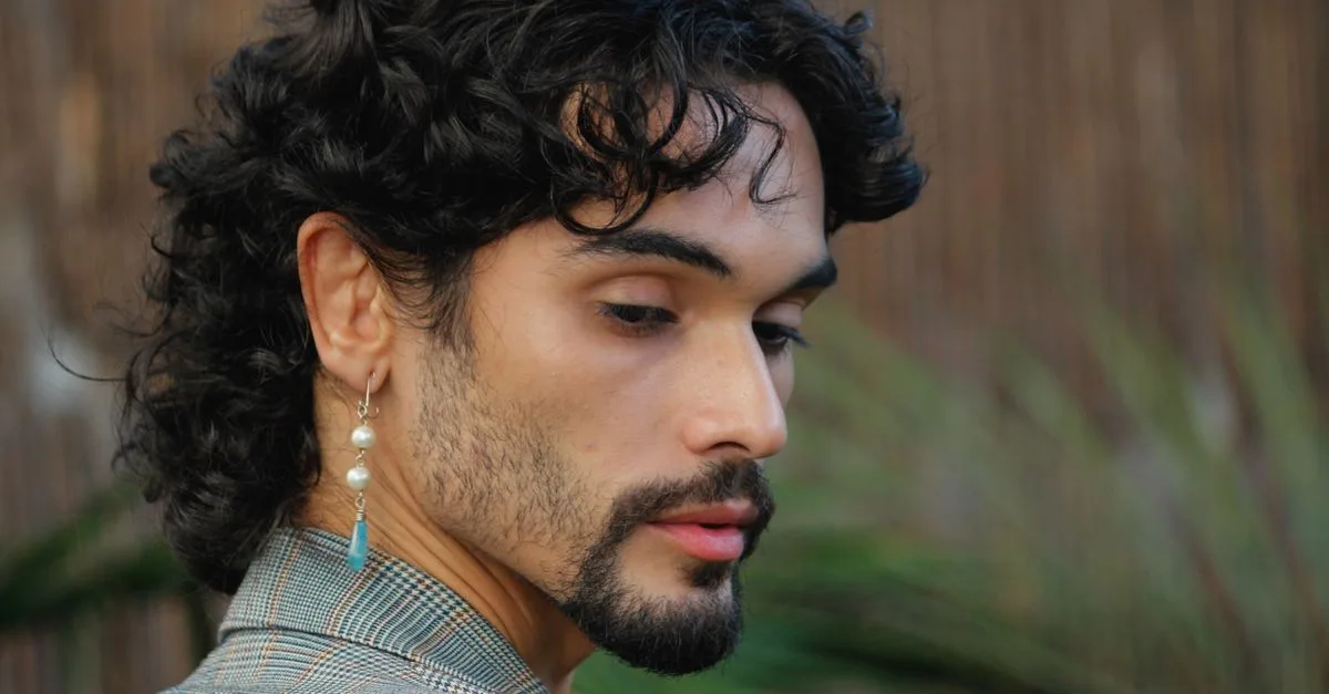 découvrez des idées de coiffures pour hommes avec cheveux bouclés, mettant en avant la longueur sur le côté pour un style moderne et élégant.